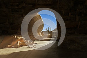 Empty tomb of Jesus Christ. Abandoned shroud and crown of thorns on the floor. Light pouring into the cave. 3d render