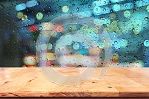 Empty top of wood table with drop on window in rainy night city