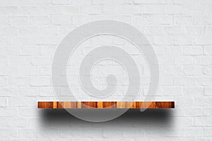 Empty top of wooden shelf with white brick wall.