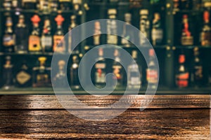 Empty the top of wooden table with blurred counter bar and bottles Background.