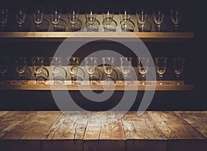 Empty the top of wooden table with blurred counter bar and drinking glass