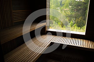 Empty traditional finnish sauna room with window and wooden wall, bench in modern luxurious hotel.