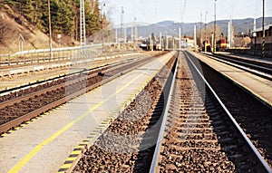 Empty train station in small city on sunny day, shallow depth of field photo, focus on concrete platform and steel rails