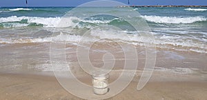 Empty transparent coffee glass stands in wet sand