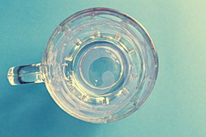 Empty and transparent glass beer jar on a blue background photo