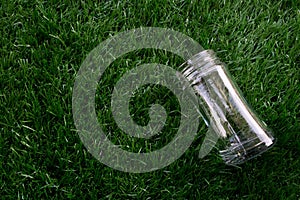 Empty transparent glass bottle lay down on the grass