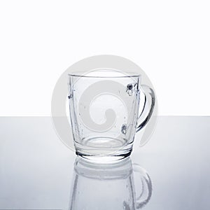 Empty transparent glass mug with water drops