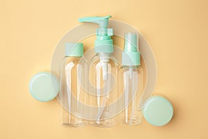 Empty travel cosmetic bottles on beige background. Minimalist bodycare beauty products for vacation or journey. Top view.