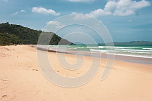 Empty tropical beach on sunny day. Duli beach in Palawan, Philippines. Surf beach. Wide beach with island on background.