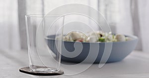 Empty tumbler glass on a white oak table with copy space and blue bowl on background