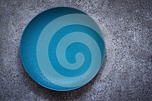 Empty turquoise ceramic plate On a concrete background. Top view