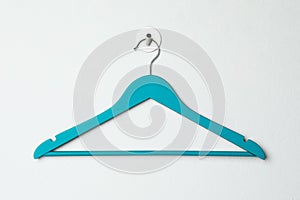 Empty turquoise clothes hanger on white wall