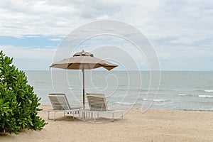 Empty two beach chairs and umbrella on a beautiful beach at sunny day - vacation in summer time