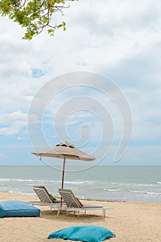 Empty two beach chairs and umbrella on a beautiful beach at sunny day - vacation in summer time