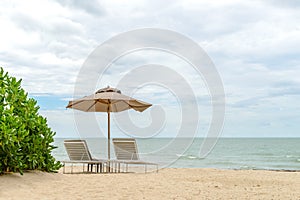 Empty two beach chairs and umbrella on a beautiful beach at sunny day - vacation in summer time