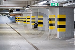 Empty underground parking lot under a modern apartment complex flat, one generic car parked, nobody, no people, lots of free