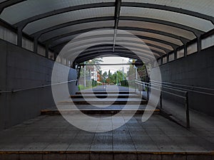 Empty underground pedestrian crossing. Light in end of tunnel. Underpass with arched roof.