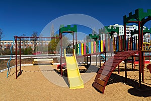 Empty urban residential infrastructure, nobody - children`s playground next to a condominium. Swing, slide, stairs, multistory