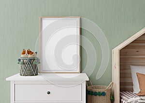 Empty vertical picture frame on green wall in modern child room. Mock up interior in scandinavian style. Free, copy