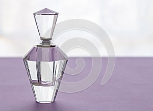 Empty vintage crystal glass perfume bottle with stopper on lilac