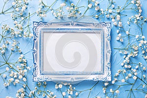 Empty  vintage frame and  fresh white gypsofila  flowers on blue textured background photo