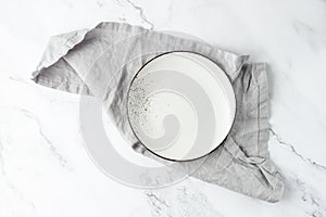 Empty vintage white plate on folded light grey soft pure linen serviette over marble board