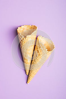 Empty wafer cone. Sweet ice cream cornet on violet background. Top view