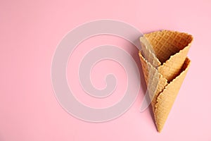 Empty wafer ice cream cones on pink background, flat lay.