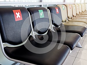 Empty waiting chairs with social distancing sign, green check mark and red cross mark