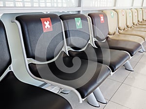 Empty waiting chairs with social distancing sign, green check mark and red cross mark