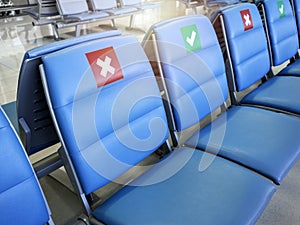 Empty waiting chairs with social distancing sign, green check mark and red cross mark