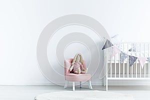 Empty wall next a to chair with a rabbit and crib with triangles photo