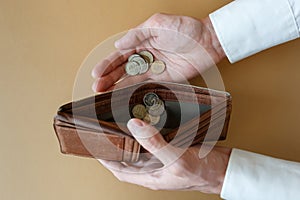 Empty wallet in the hands of a man on a plain background