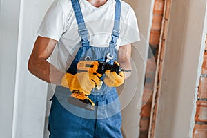 Empty walls. Young man working in uniform at construction at daytime