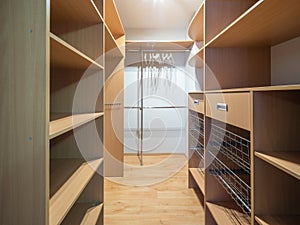 Empty wardrobe cloackroom in luxury apartment. Wooden shelves.