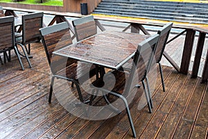 Empty wet wooden table and chairs in a street cafeteria during the rain. Street city life in the rain