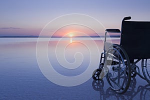 Empty wheelchair on the lake at sunset with beautiful colours