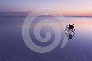Empty wheelchair on the lake at sunset with beautiful colours