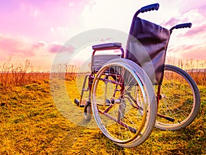 Empty wheelchair on the meadow at sunset. Miracle concept. Healed person raised and went away