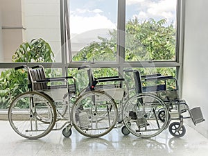 Empty wheelchair parked in front of hospital window.