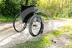 Empty wheelchair parked in park, health care concept, with sun flare