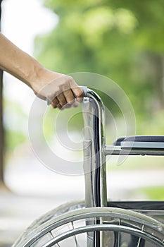 Empty wheelchair pushed by nurse`s hands