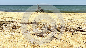 Empty wheelchair stands on the seashore after a storm.