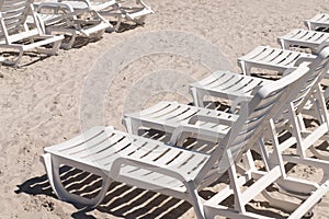 Empty white beach relaxation chairs on sand beach