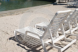 Empty white beach relaxation chairs on sand beach