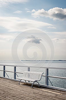 Empty white bench on pier at coastline Baltic sea