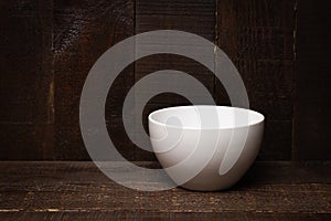 Empty white bowl on rastic wooden background. photo