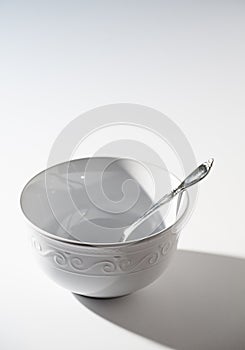 Empty White Bowl with Spoon on a White Background
