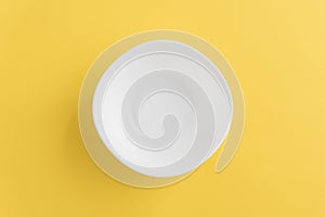 Empty white bowl on yellow background, top-down view