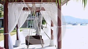 Empty white canopy swing or patio swing by the beach.